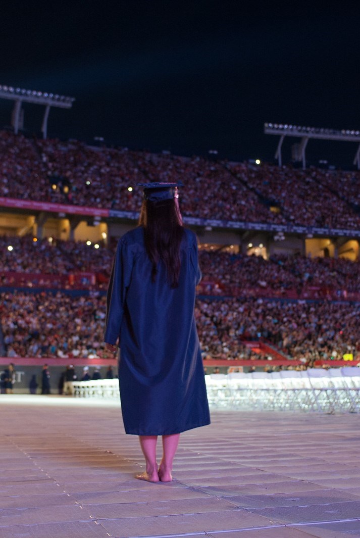 University graduate on stage wearing cap and gown